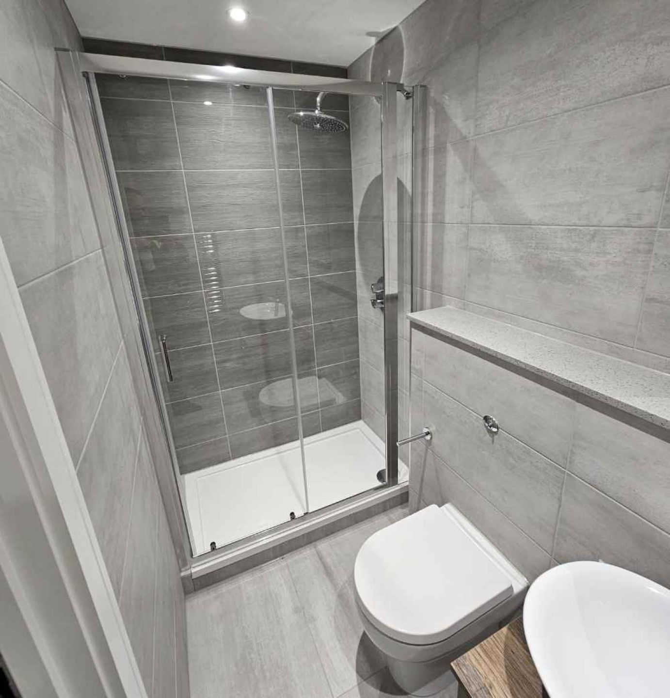 Toilet and shower room with grey slate tiles, toilet and basin.