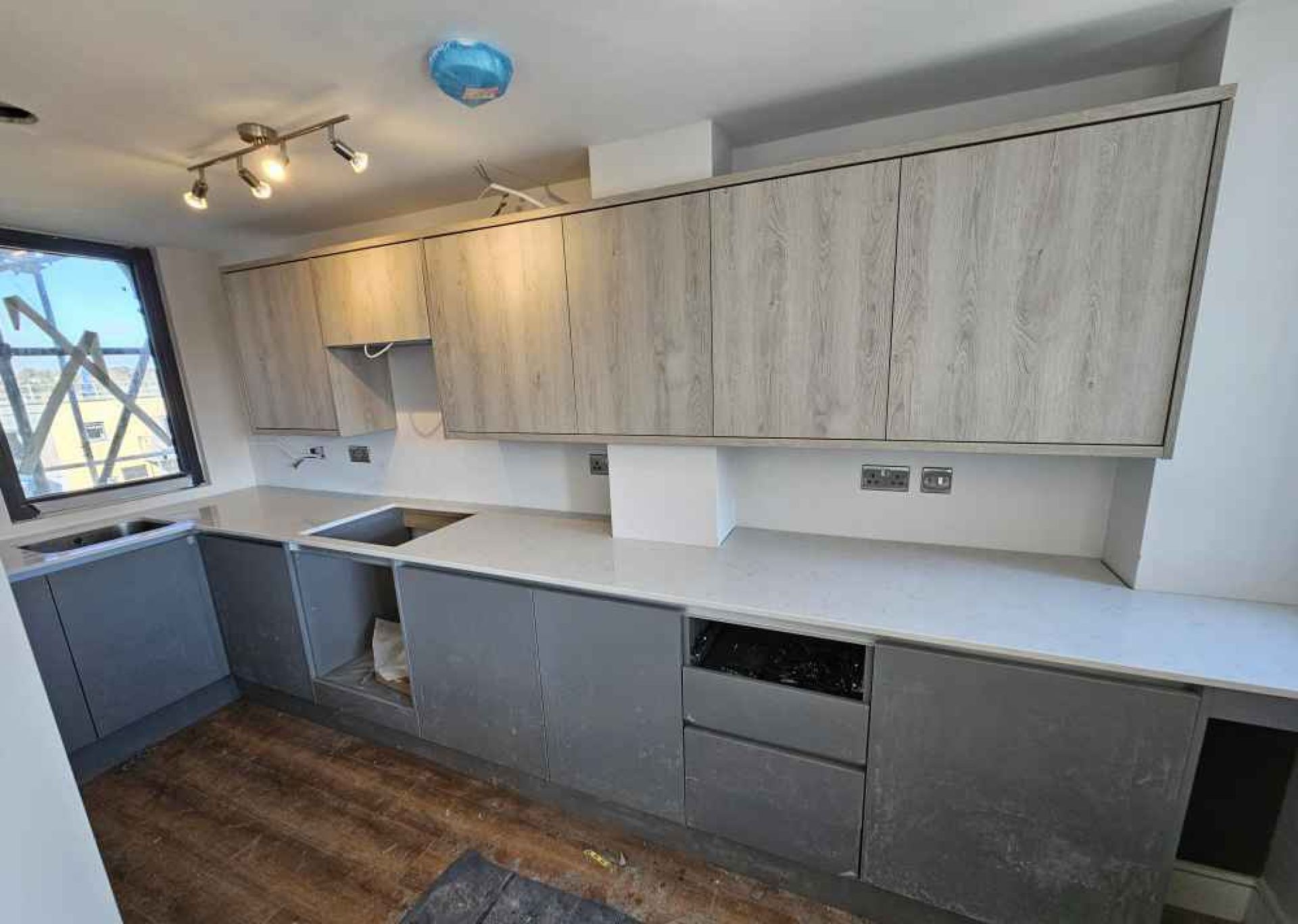 Kitchen area at the halfway stage of development. Cupboards on walls with kitchen top drawers.