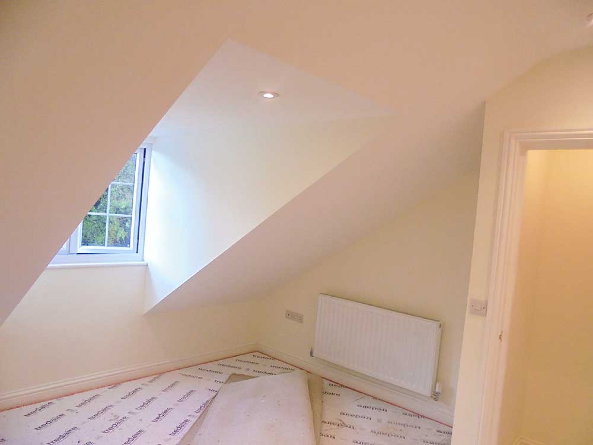 Completed plastering and painting in upstairs bedroom with spot lights and window.