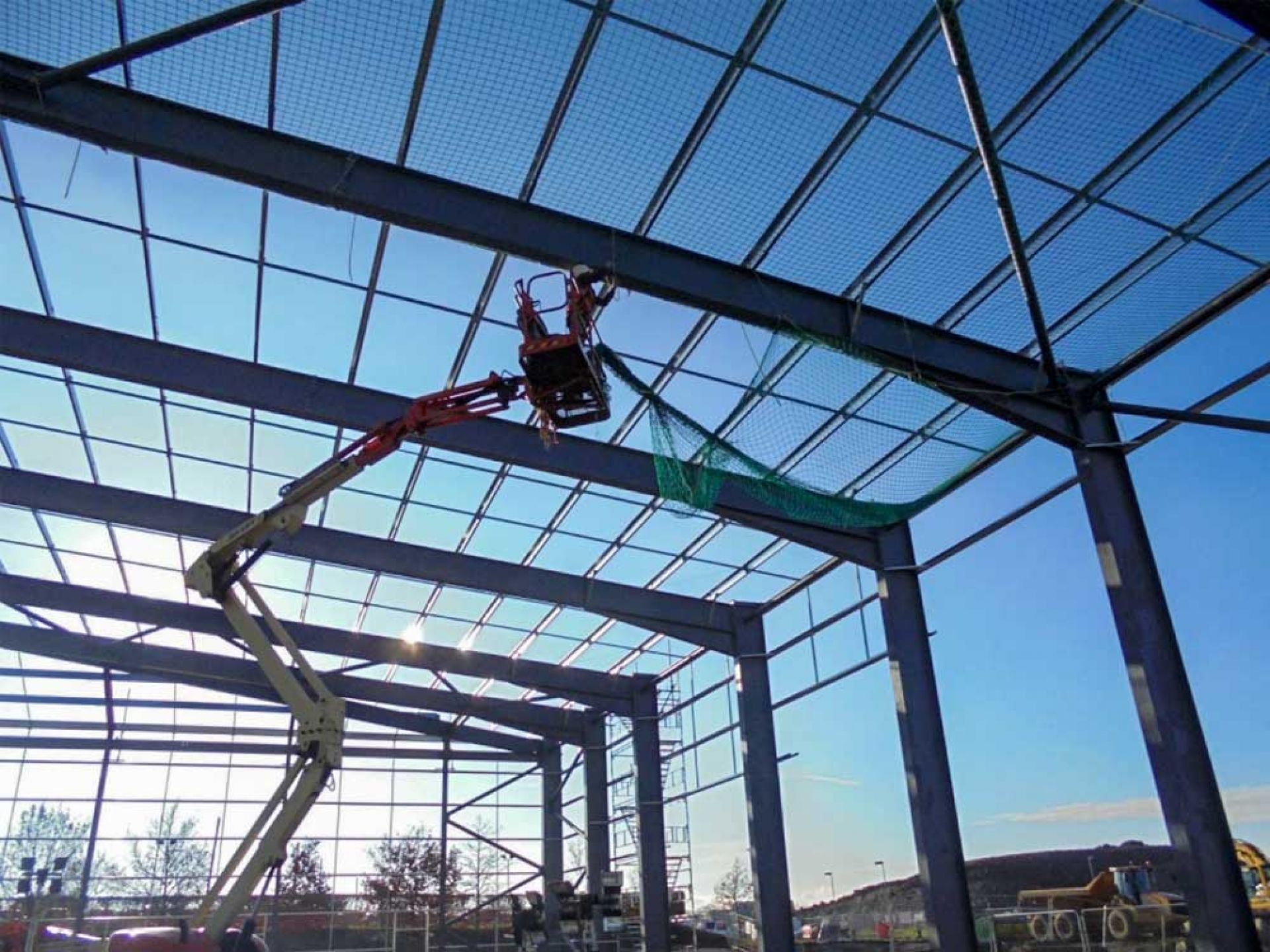 Workman working up high on the roof of new warehouse development.