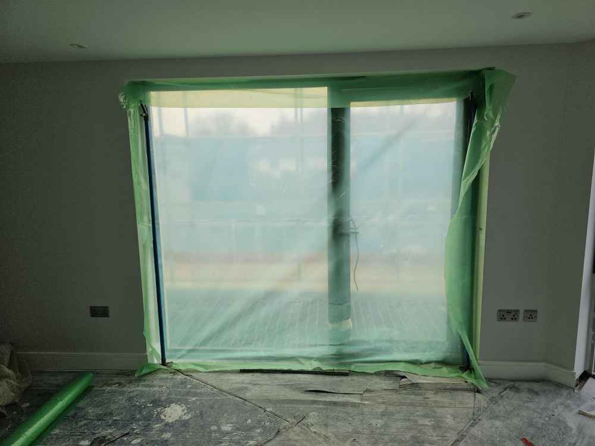 Large window with green plastic sheet over it that has just been installed.