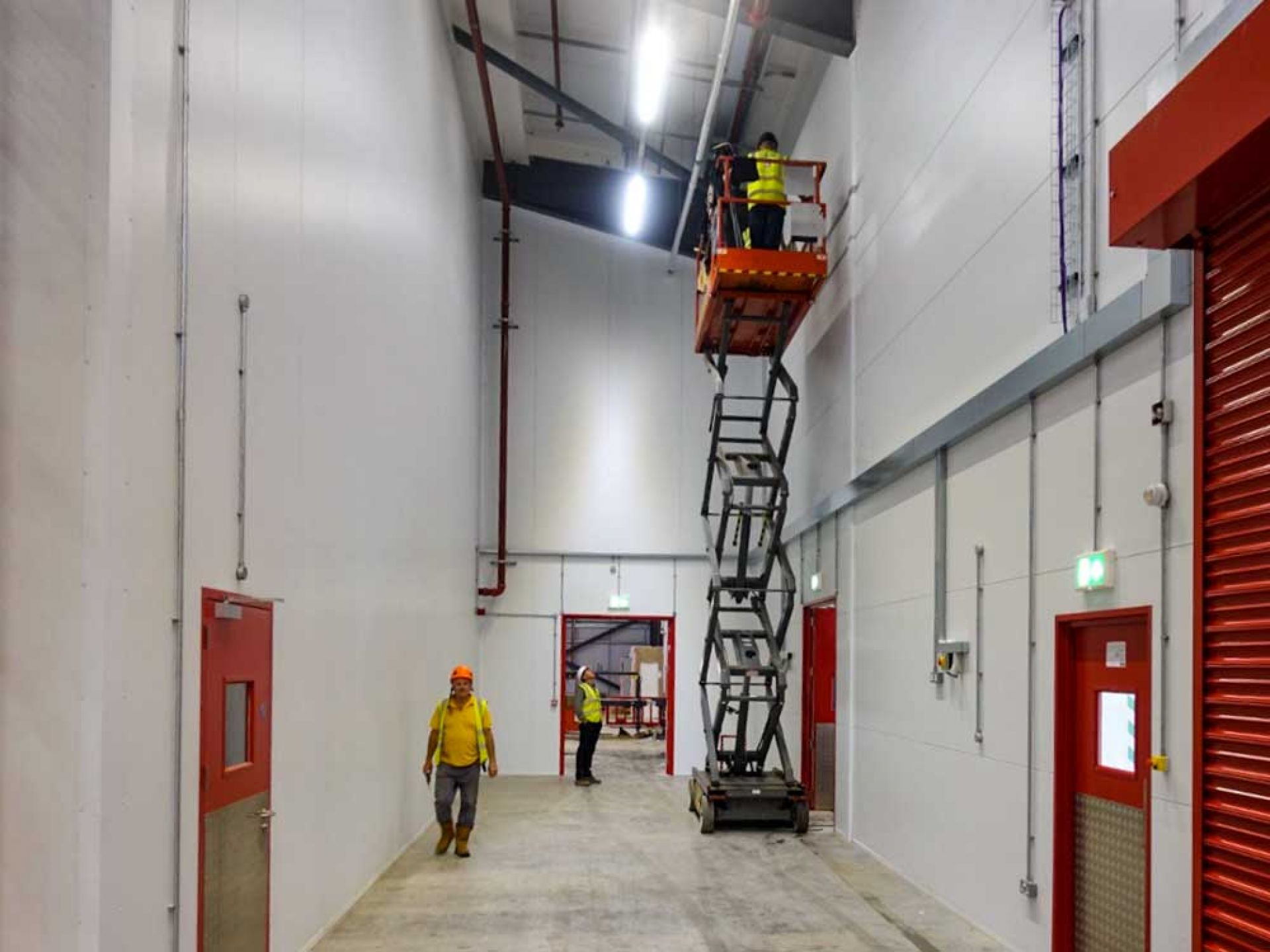 Various workmen adding finishing touches to completed warehouse.