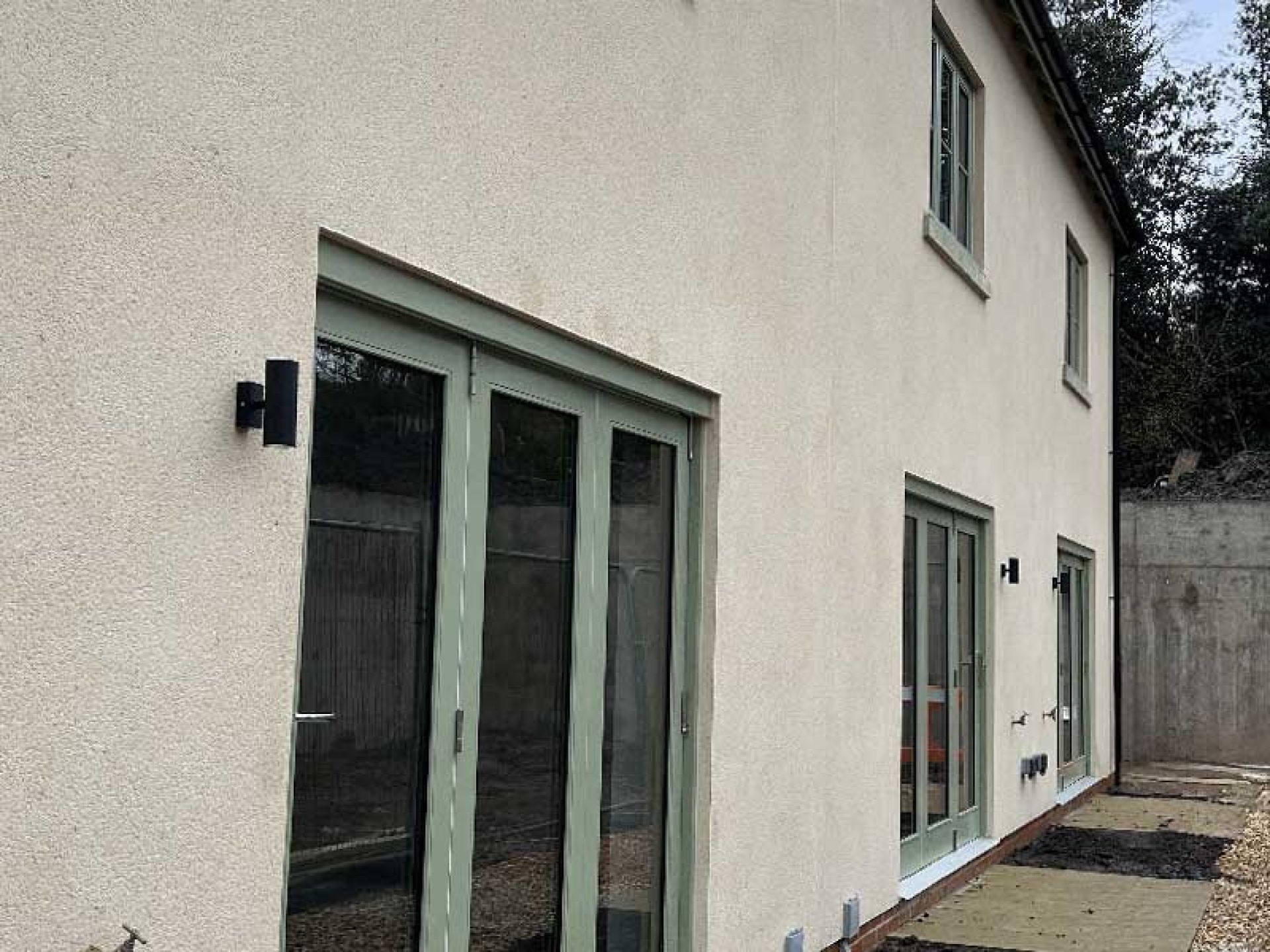 Back garden of one of the terraced houses at the Bourton Mill site looking at the patio and rear windows.