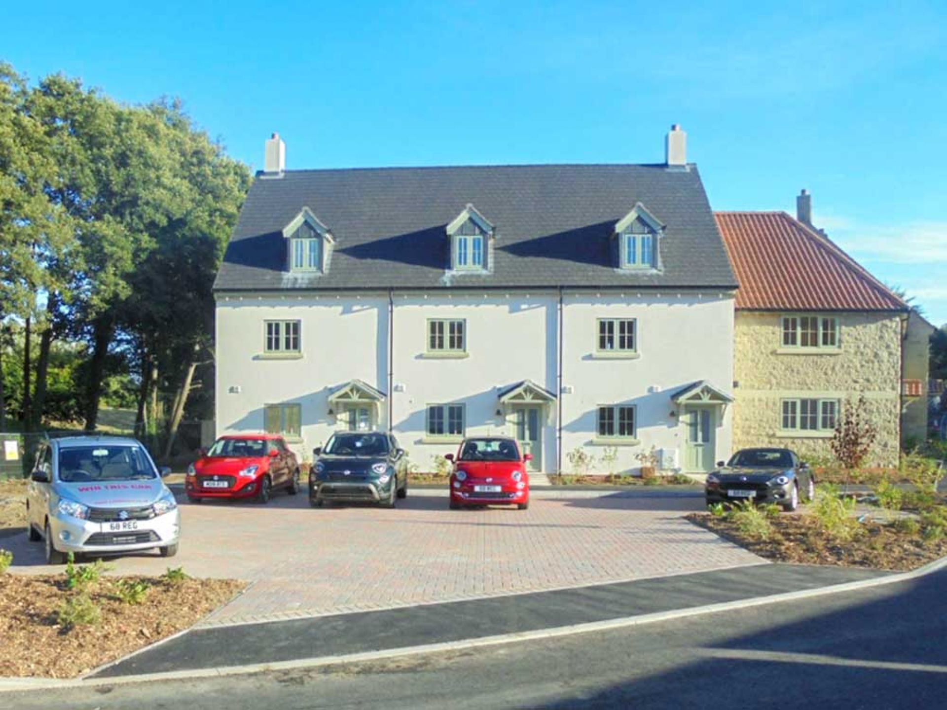 Three large white houses in the middle of a new housing development.