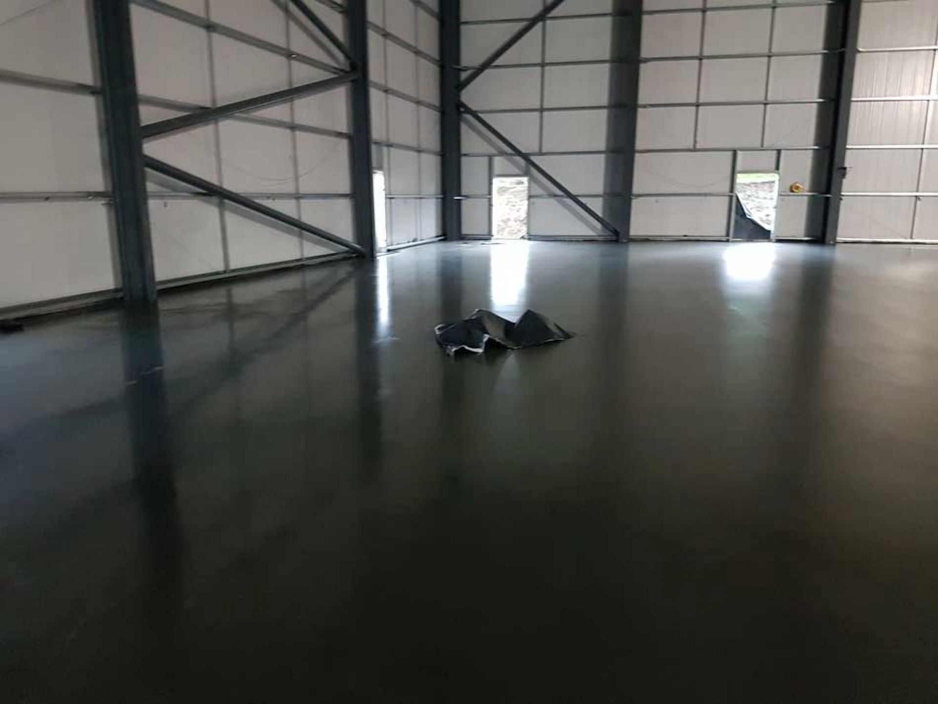 Uk warehouse construction with dark floor and various doors leading outside.