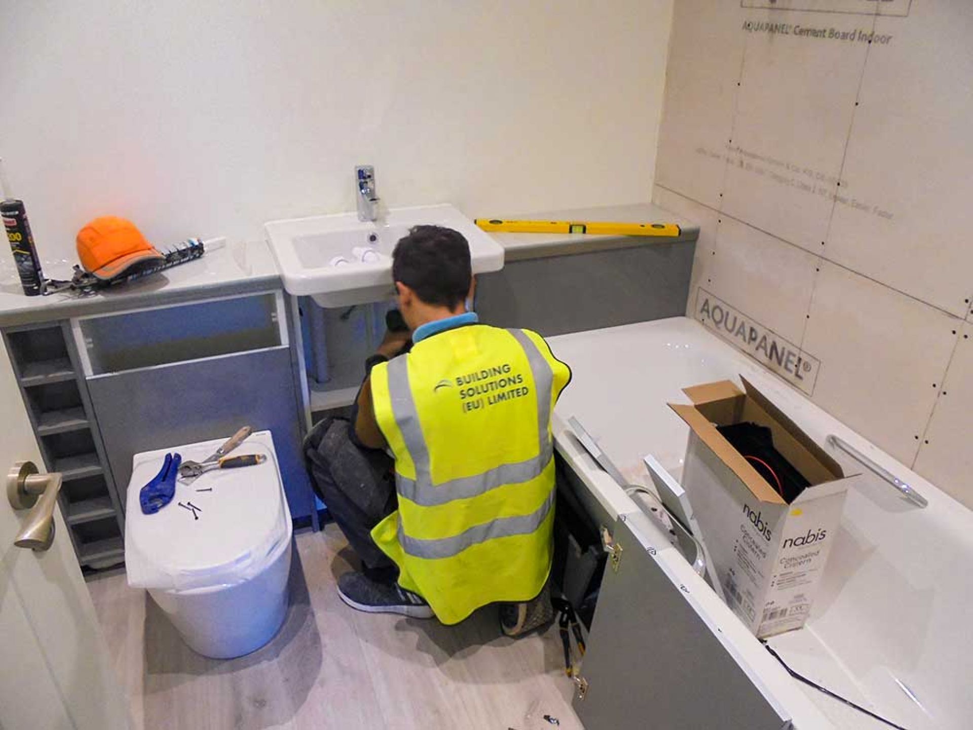 Construction man working on plumbing for the bathroom area.