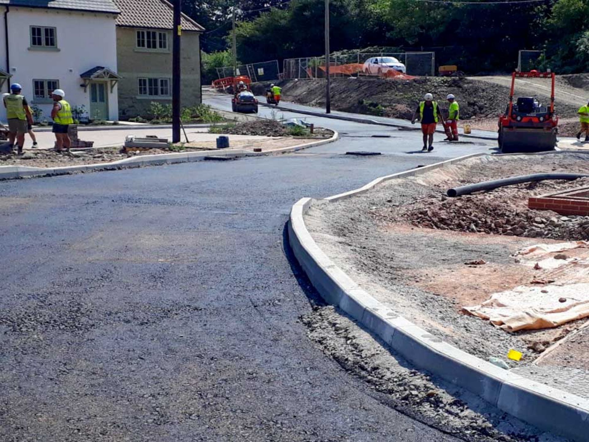 Tarmac applied to highway construction with people working on the road.