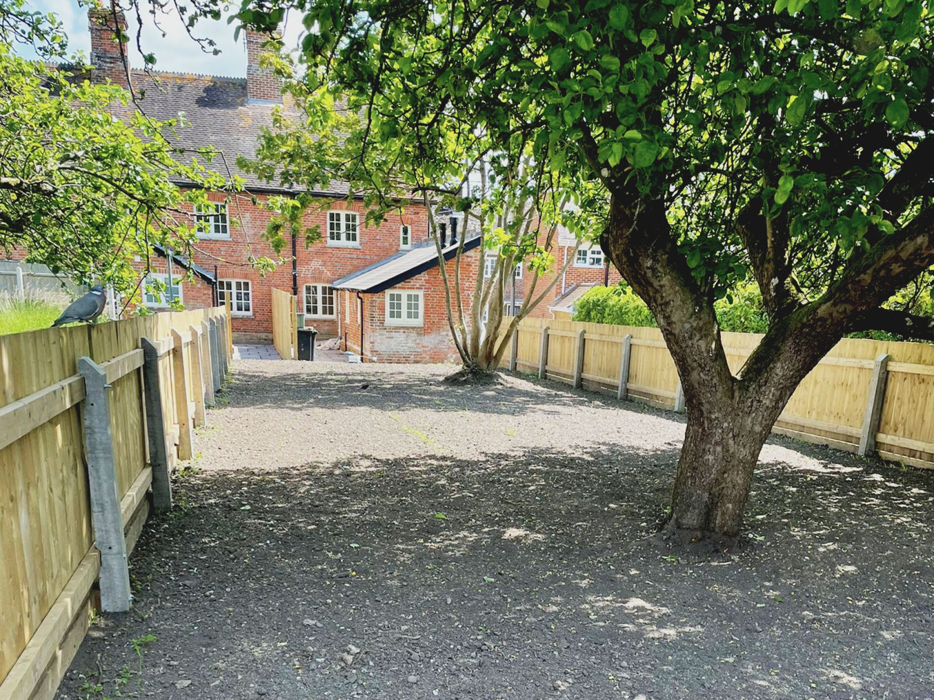 Completed outside drive way of crandborne house with gravel floor and large tree.