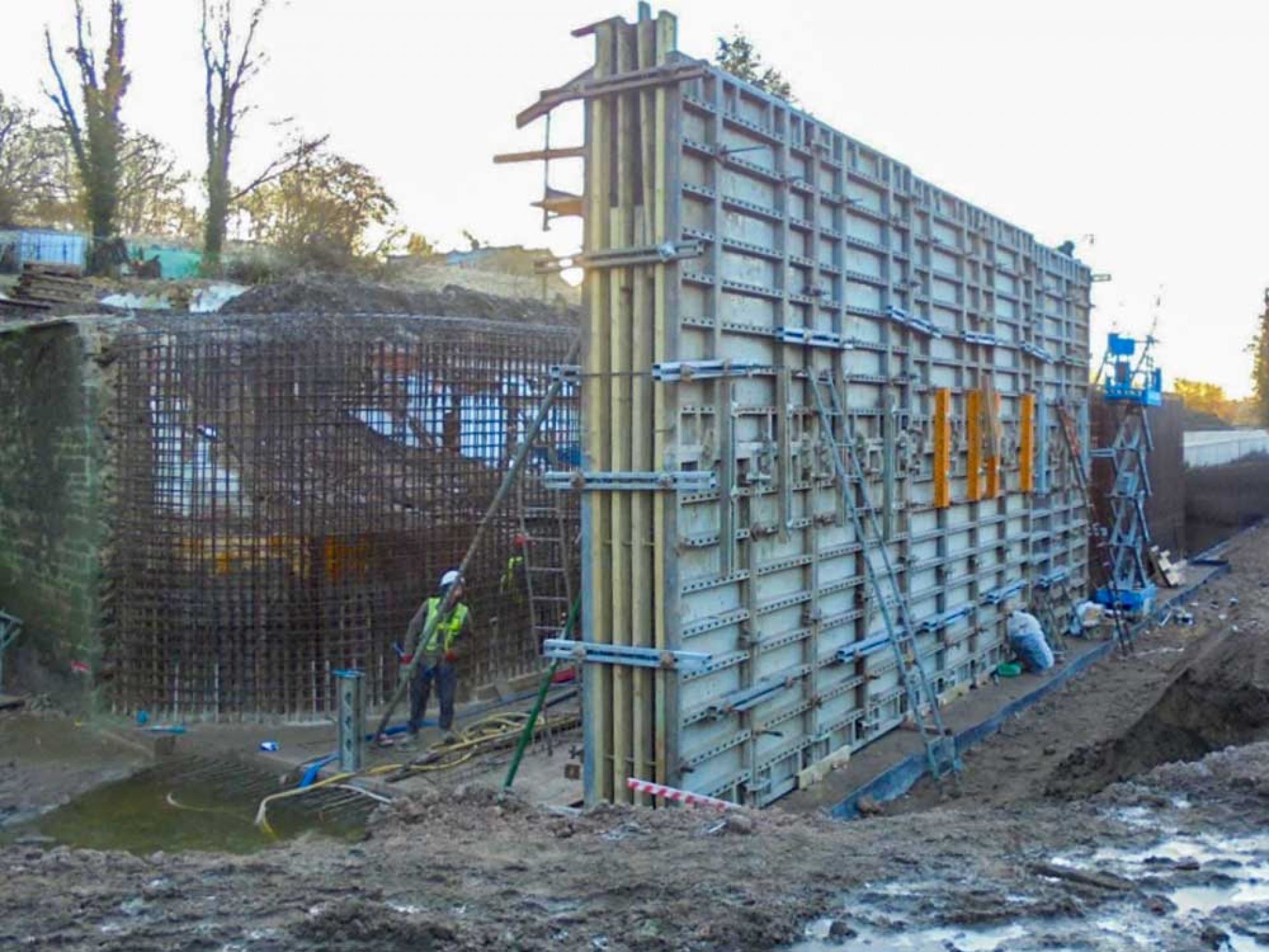 Man stood next to large concrete wall during consruction.