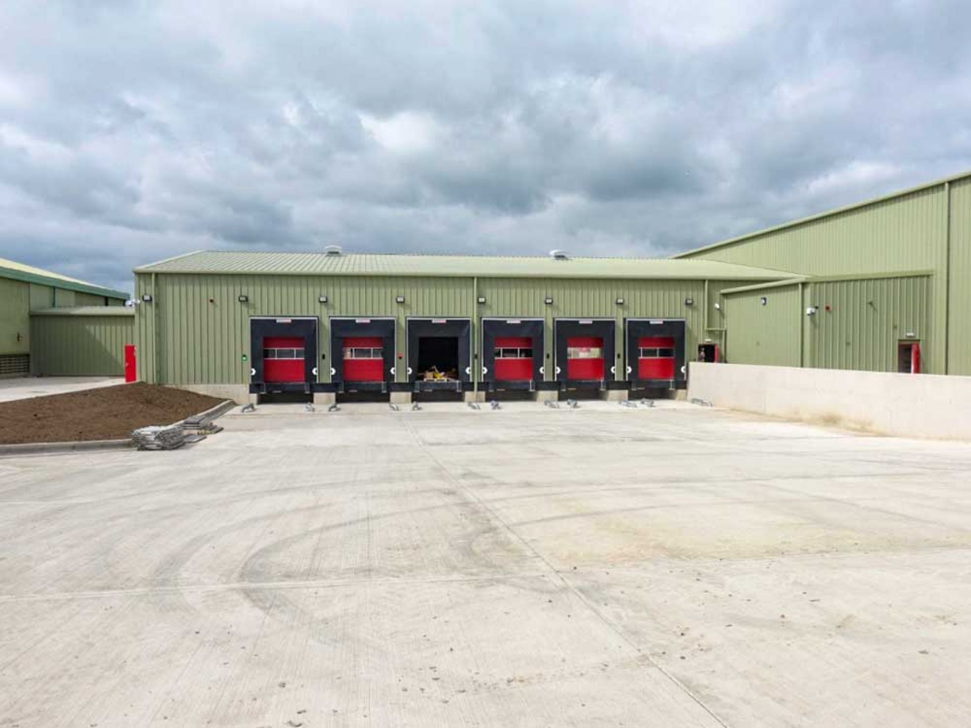 Large green completed warehouse development with red loading bays.