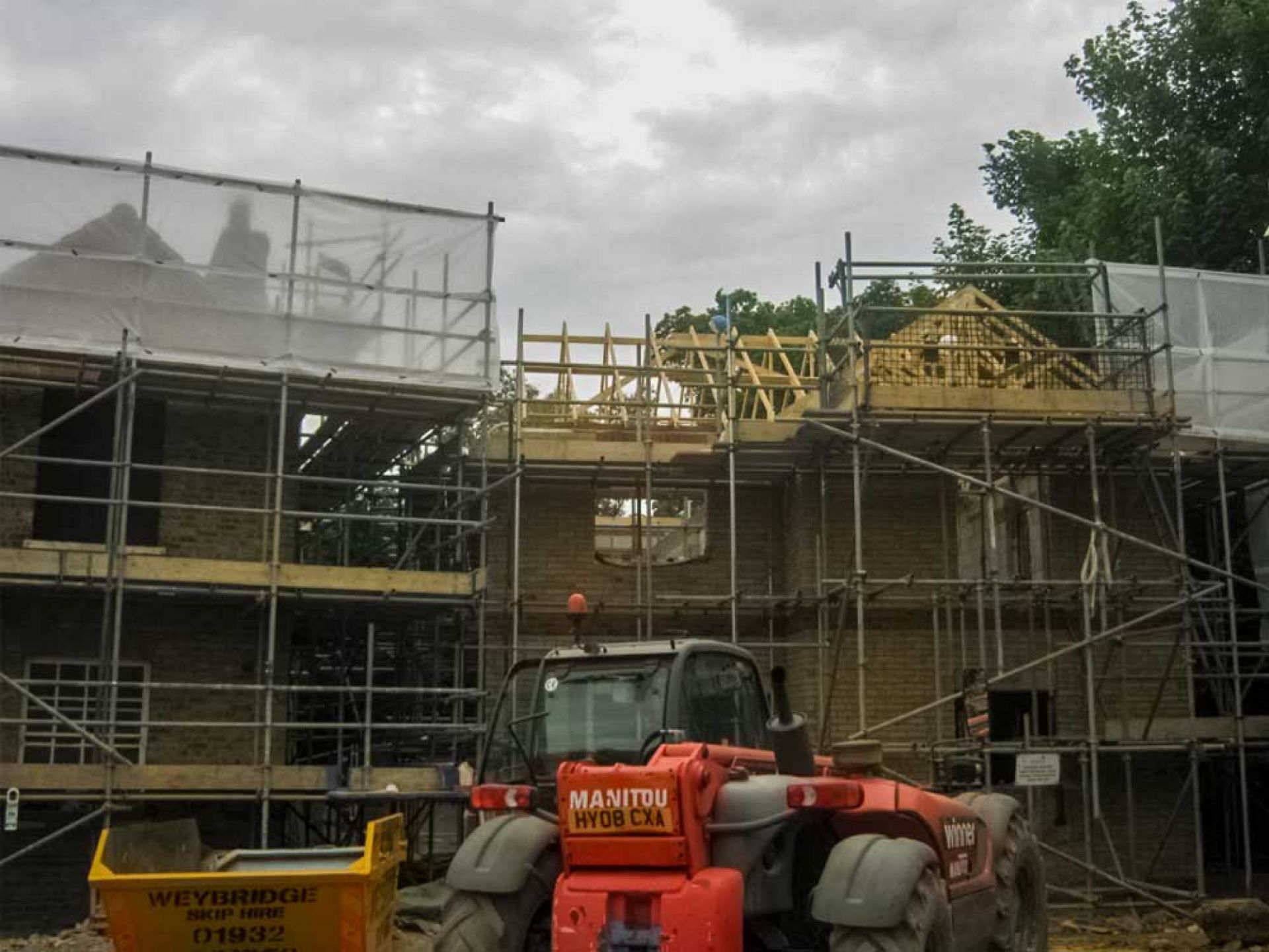 Construction of house extension and new build with large machinery outside and scaffolding.