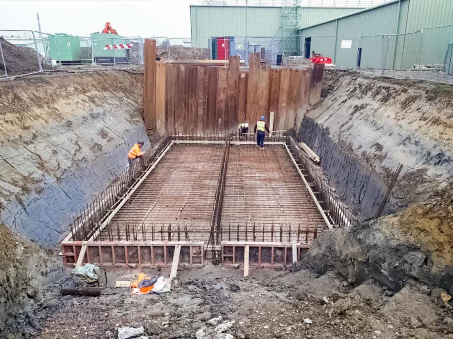 Large hole dug with construction workers inside.