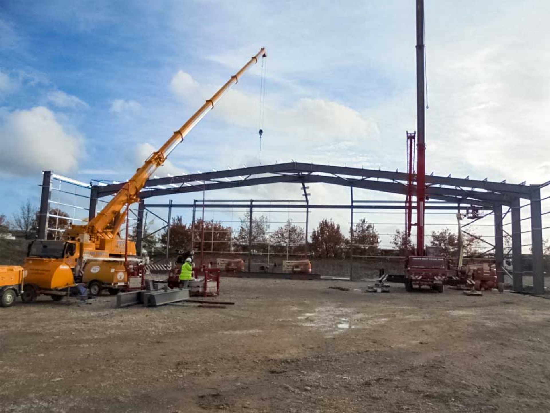 Large construction machinery working on structure of warehouse development.